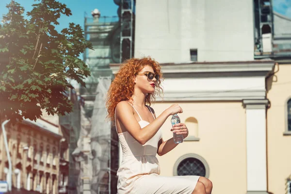 Genç kırmızı saçlı kız bir şişe su içme.