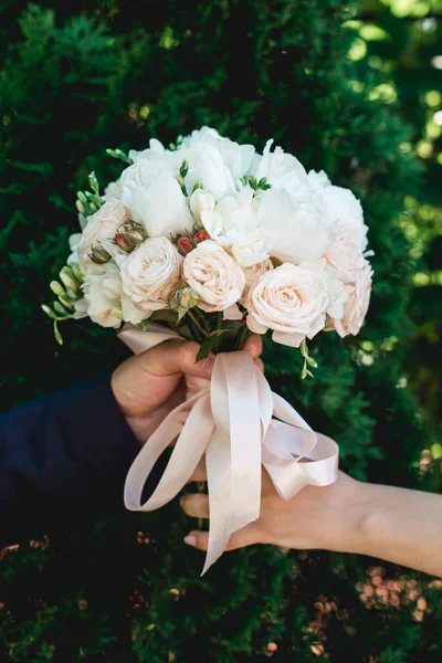 Наречена і наречена тримає розкішний весільний букет з білих півоній і троянд в хвойних кущах — стокове фото