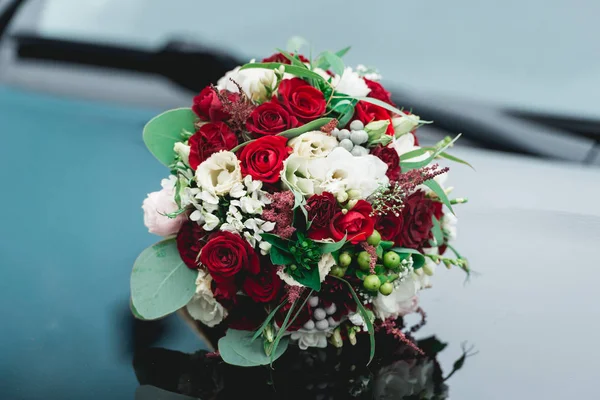 Ramo de boda de rosas blancas y rojas en una capucha de coche — Foto de Stock