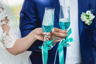 güzel gelin ve damat şampanya ile toasting, sabah düğün. Mavi şarap şık gözlük tutan eller