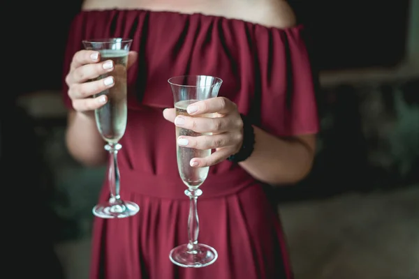 Девушка в гранатовом платье и с французским маникюром держа в руках два бокала с шампанским — стоковое фото