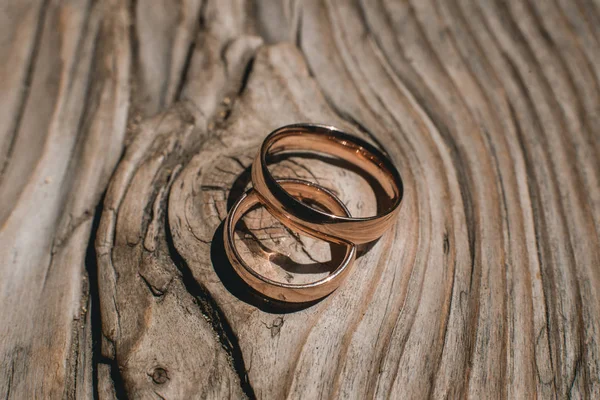 Par de anéis de ouro do casamento no fundo rústico de madeira amarelo — Fotografia de Stock