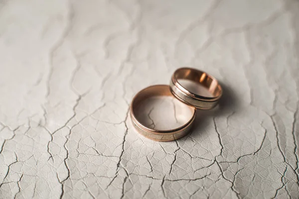Par de anillos de oro de la boda en la piel agrietada — Foto de Stock