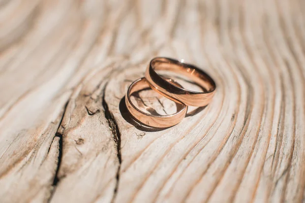 Par de anillos de oro de la boda en el fondo rústico de madera amarillo — Foto de Stock
