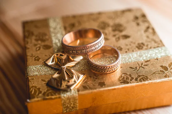 Pair of wedding golden rings on the golden gift box — Stock Photo, Image