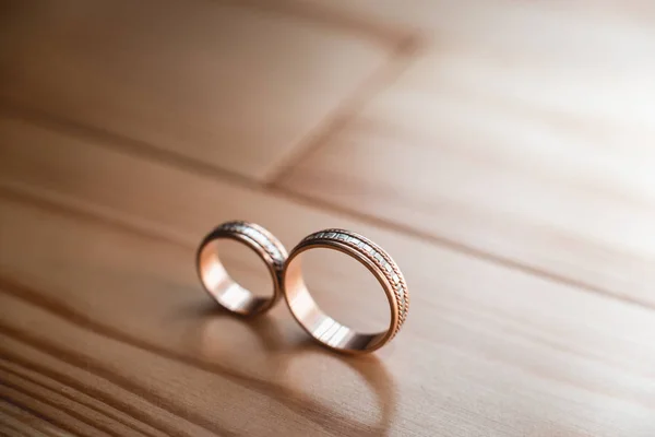 Par de anillos de oro de la boda en el suelo de madera amarillo — Foto de Stock
