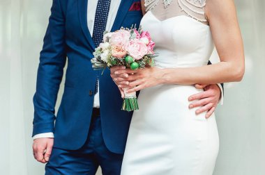 Güzel gelin düğün buket pembe Gül ve peonies ile tutar. Damat kucaklama kadın bel tarafından.