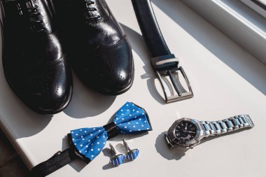 Siyah deri ayakkabı ve kemer, izle, mavi kravat ve kol düğmeleri, bir beyaz pencere eşiğinde. Resmi elbise için aksesuar.