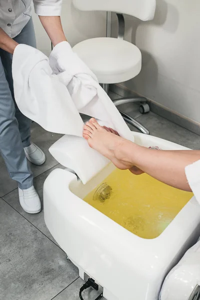 Hermosas piernas de una chica en un albornoz blanco. moderno salón de belleza — Foto de Stock