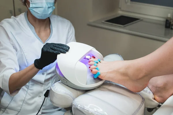 Pedicura tratamiento de pies y uñas con productos cosméticos y lámpara UV — Foto de Stock