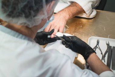 Bir manikürcünün tırnaklarını keserken yakın plan fotoğrafı.