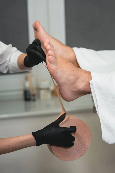 Therapeutische Behandlung des Beines mit beigem Physio-Tape — Stockfoto