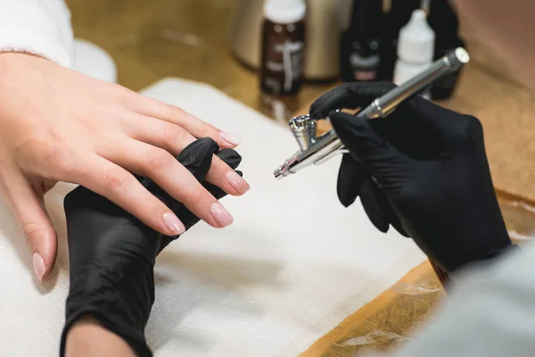 Close-up shot van een vrouw in een nagel salon ontvangen een manicure door een schoonheidsspecialiste met airbrush. Vrouw krijgt nail manicure. — Stockfoto