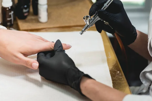 Nahaufnahme einer Frau in einem Nagelstudio, die von einer Kosmetikerin mit Airbrush gepflegt wird. Frau bekommt Nagelmaniküre. — Stockfoto