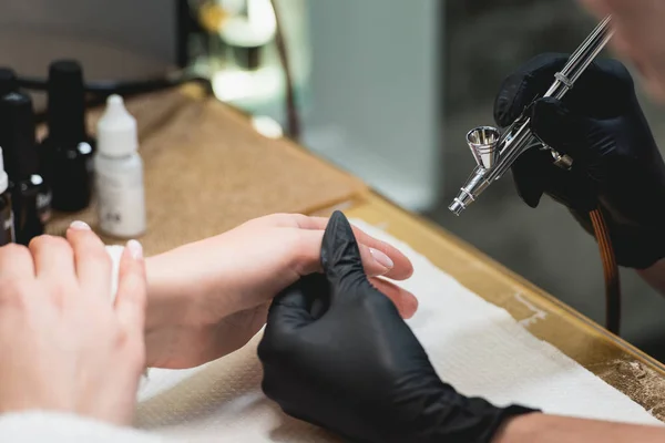 Close-up shot van een vrouw in een nagel salon ontvangen een manicure door een schoonheidsspecialiste met airbrush. Vrouw krijgt nail manicure. — Stockfoto