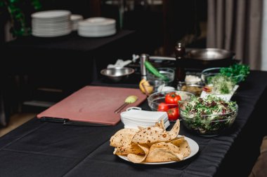 Taco için ürünlerle dolu bir masa. Restorandaki şef müşterilerin önünde lahana salatası ve salsa soslu baharatlı karidesli taco yapacak.