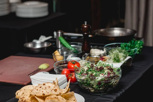 Taco için ürünlerle dolu bir masa. Restorandaki şef müşterilerin önünde lahana salatası ve salsa soslu baharatlı karidesli taco yapacak.