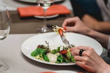Kadın brie peyniri, karahindiba ve çilek salatası yiyor.
