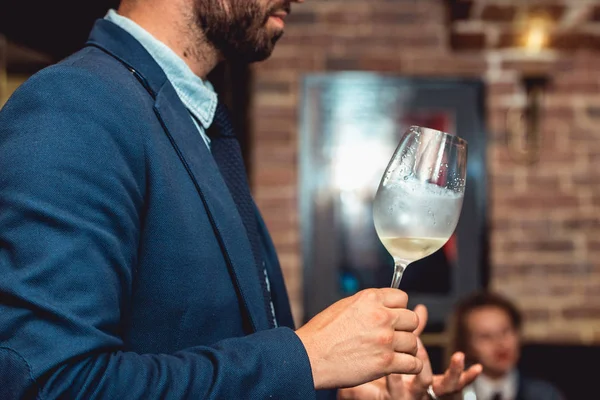 穿蓝色西装的男人拿着一杯白葡萄酒 — 图库照片