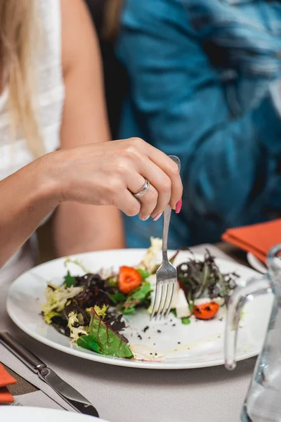 Женщина ест салат с сыром бри, одуванчиками и клубникой . — стоковое фото