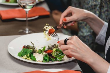 Kadın brie peyniri, karahindiba ve çilek salatası yiyor.