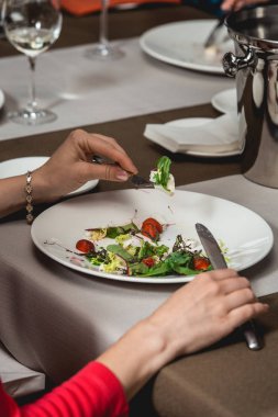 Kadın brie peyniri, karahindiba ve çilek salatası yiyor.