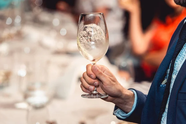 El hombre sostiene una copa de vino tinto. la gente considera el color del vino y probar cómo huele en diferentes vasos — Foto de Stock