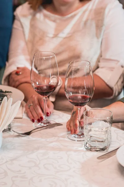 Mujer sostiene una copa de vino tinto. la gente considera el color del vino y probar cómo huele en diferentes vasos — Foto de Stock
