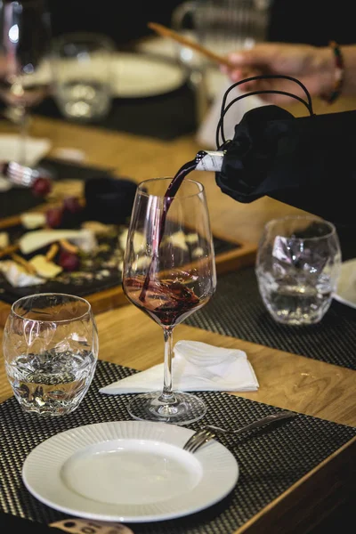 Sommelier a la cata de vinos vertiendo vino de una botella en un vaso a la cata de vinos ciegos — Foto de Stock