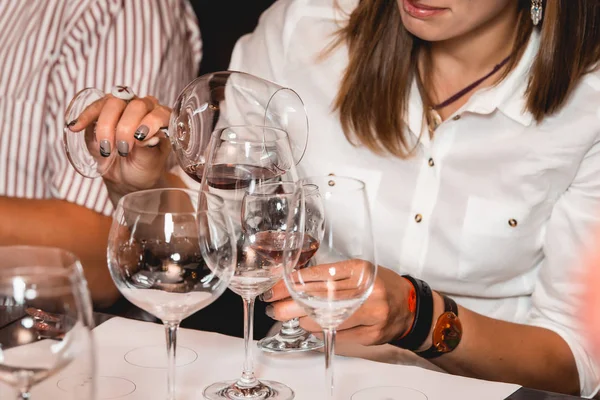 Mujer sostiene un vaso de vino. la gente considera el color del vino y probar cómo huele en diferentes vasos — Foto de Stock