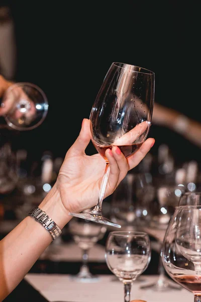 Donna tiene un bicchiere di vino rosso. la gente considera il colore del vino e prova come profuma in bicchieri diversi. — Foto Stock