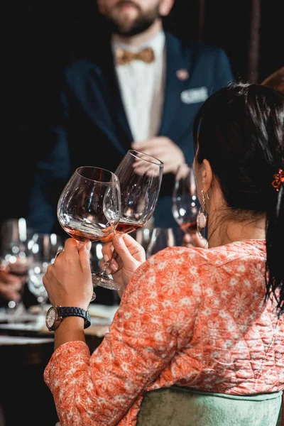 Mujer sostiene un vaso de vino. la gente considera el color del vino y probar cómo huele en diferentes vasos — Foto de Stock