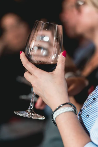 Mujer sostiene una copa de vino tinto. la gente considera el color del vino y probar cómo huele en diferentes vasos — Foto de Stock