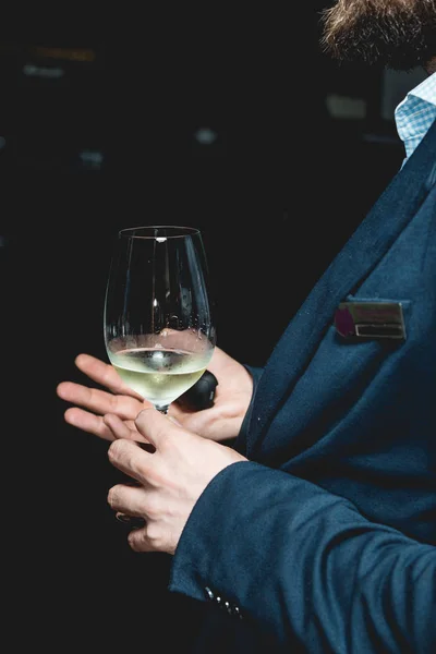 El hombre sostiene una copa de vino. la gente considera el color del vino y probar cómo huele en diferentes vasos — Foto de Stock