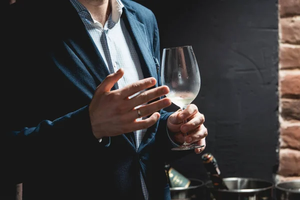 El hombre sostiene una copa de vino. la gente considera el color del vino y probar cómo huele en diferentes vasos — Foto de Stock