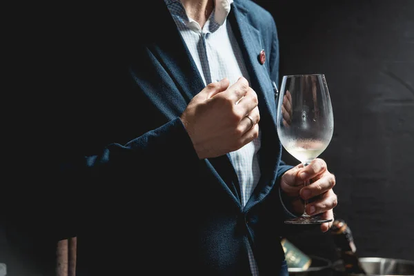 El hombre sostiene una copa de vino tinto. la gente considera el color del vino y probar cómo huele en diferentes vasos — Foto de Stock