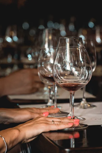 Mujer sostiene una copa de vino tinto. la gente considera el color del vino y probar cómo huele en diferentes vasos — Foto de Stock