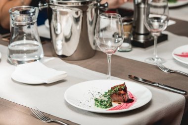 taze Izgara Barbekü Izgara sığır eti biftek ve sos yeşil yaprak salata ile beyaz tabakta. bir tabloda bir lokantada çorba sosu küçük sürahi cam servis