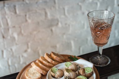 Salyangoz geleneksel seramik içinde otlar tereyağlı ekmek bir ahşap tahta üzerinde pan. Şarap