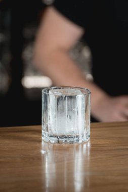 Siyah arka planda kokteyl bardağında büyük bir buz parçası.