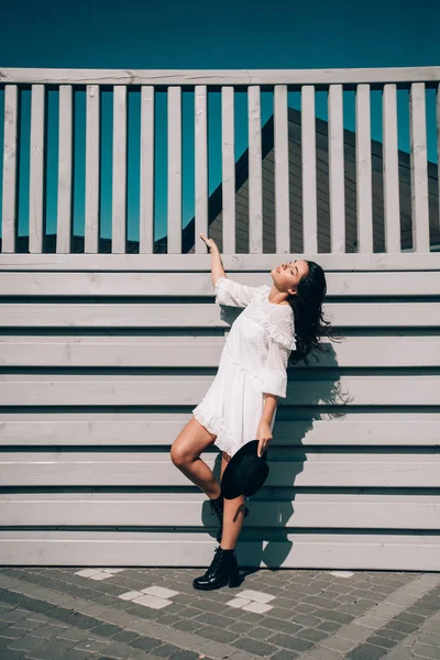 Sunny lifestyle portrait of young stylish hipster woman, wearing trendy white dress, black hat and boots — 스톡 사진