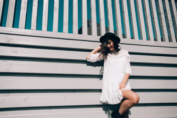 Sunny lifestyle portrait of young stylish hipster woman, wearing trendy white dress, black hat and boots — 스톡 사진