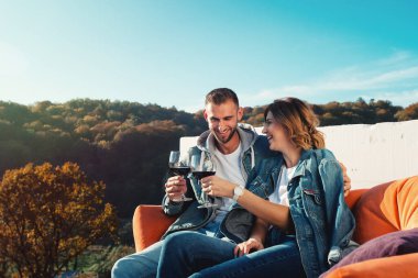 Genç bir çift yeni bir ev satın almayı kutluyor. Ellerinde kırmızı şarapla gülümseyen karı koca.