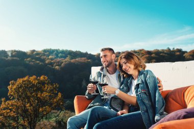 Genç bir çift yeni bir ev satın almayı kutluyor. Ellerinde kırmızı şarapla gülümseyen karı koca.