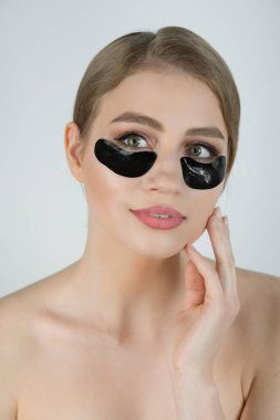 Göz Derisi Siyah Yama Altında. Nemlendirici Kolajen Maske Pedi ile Beyaz Arkaplanda Taze Cilt Üzerine Güzel Genç Kadın Yüzü 'nün Kapanışı. Yüksek Çözünürlük.