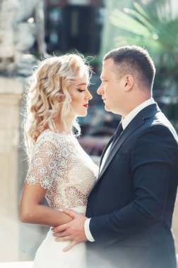 Gelin ve damat. Takım elbiseli bir adam ve düğün günü beyaz elbiseli sarı saçlı bir kadının yakın plan portresi..