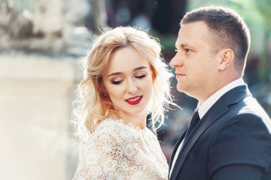 Gelin ve damat. Takım elbiseli bir adam ve düğün günü beyaz elbiseli sarı saçlı bir kadının yakın plan portresi..