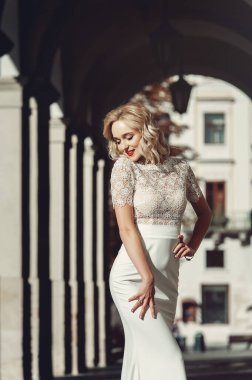 Güzel Mutlu Kıvırcık Saçlı Gelin 'in Portresi. Moda elbisesi ve Kırmızı Dudaklı Makyaj. Gelin, eski bir evin kemerinde duruyor.