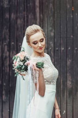 Güzel genç gelin elinde pastel bej renkte gül buketini Fransız manikürlü tutuyor. Yakın görünüm