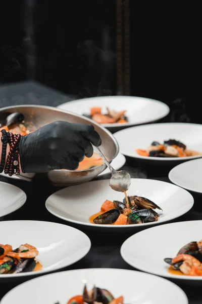 Chief in a restaurant serving seafood with sauce on a plate